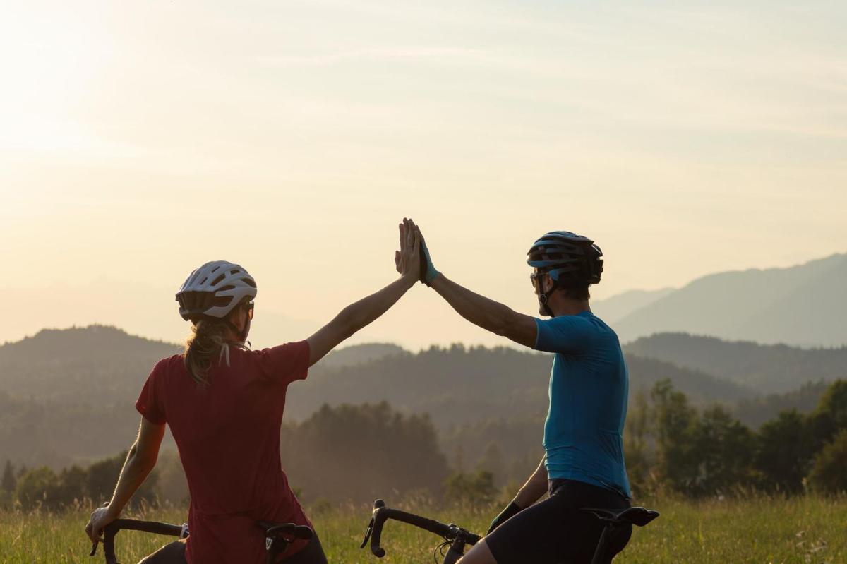 Zwei Radfahrende klatschen sich vor der Abendsonne ab